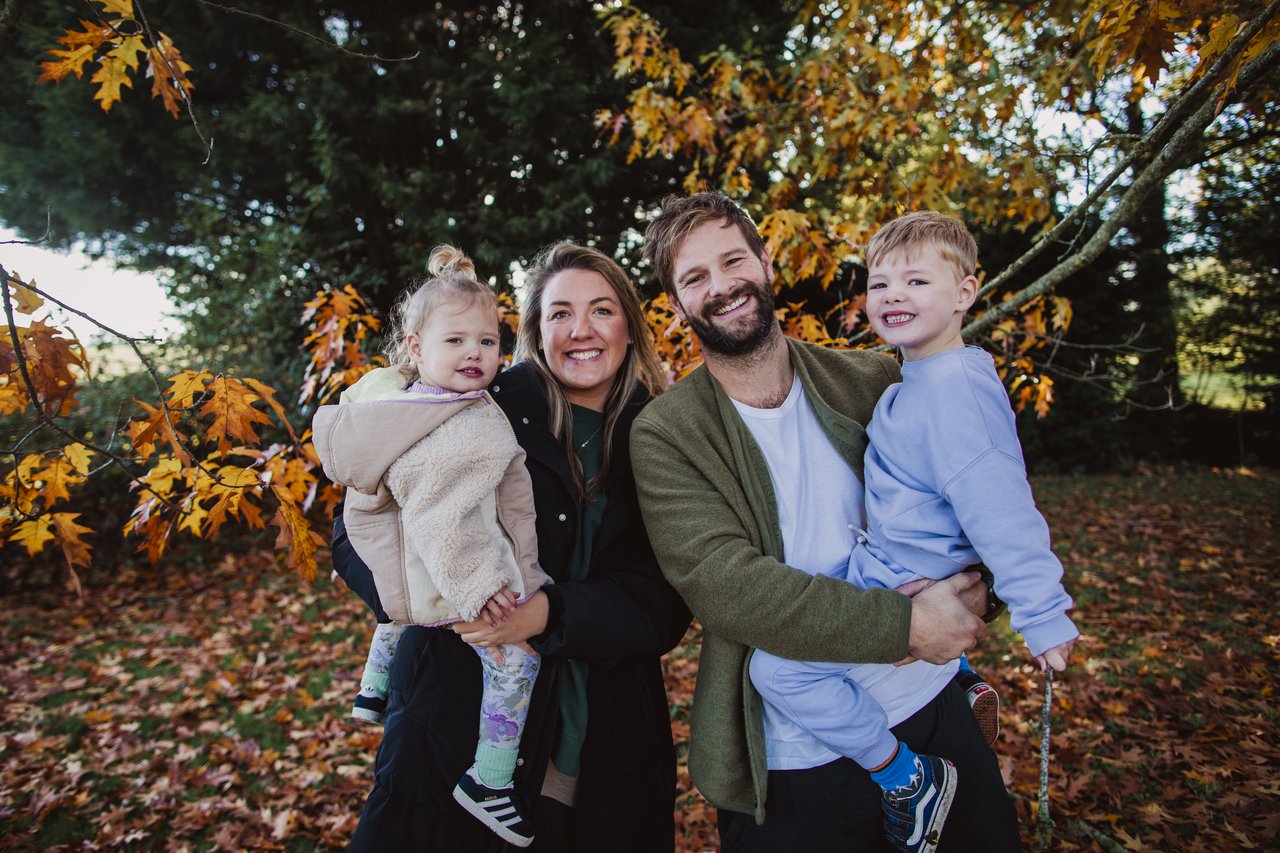 Chelsie and her family stood in the woodland  surrounded by autumn trees