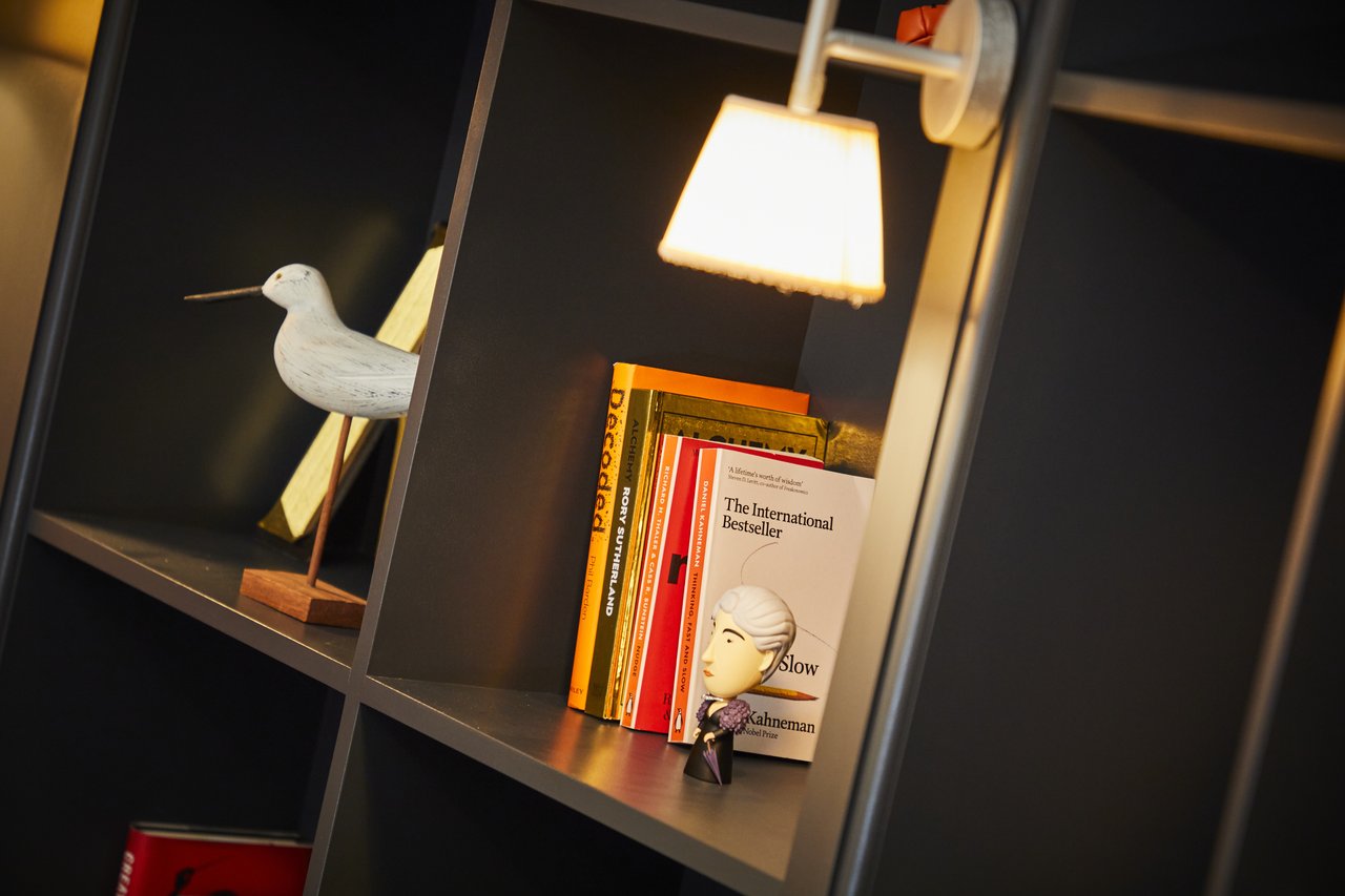 A close-up of a bookcase, with a model bird and books on some of the shelves.