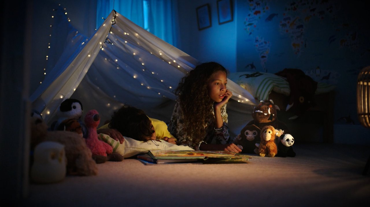 A young girl in her bedroom den at night, playing with her stuffed animals