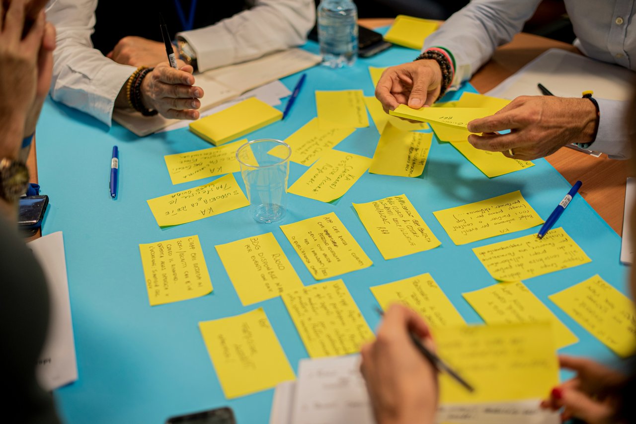 A group of people using post-it notes to share ideas. The notes are yellow, on a blue background