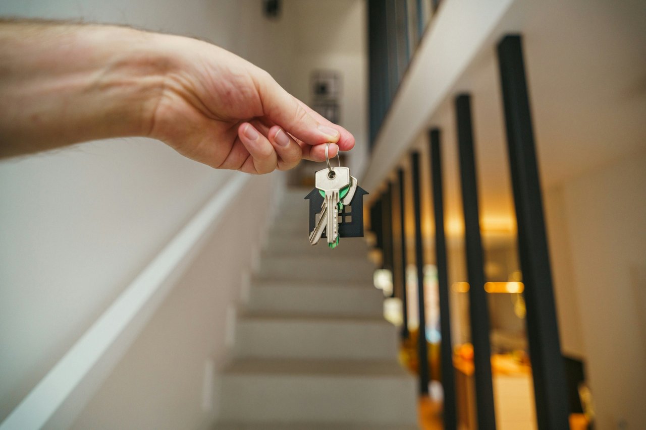 A person holds their new house keys in front of their stairs