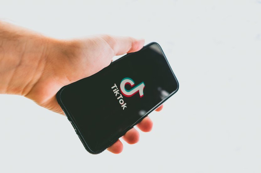 A hand holding a smartphone featuring the TikTok logo