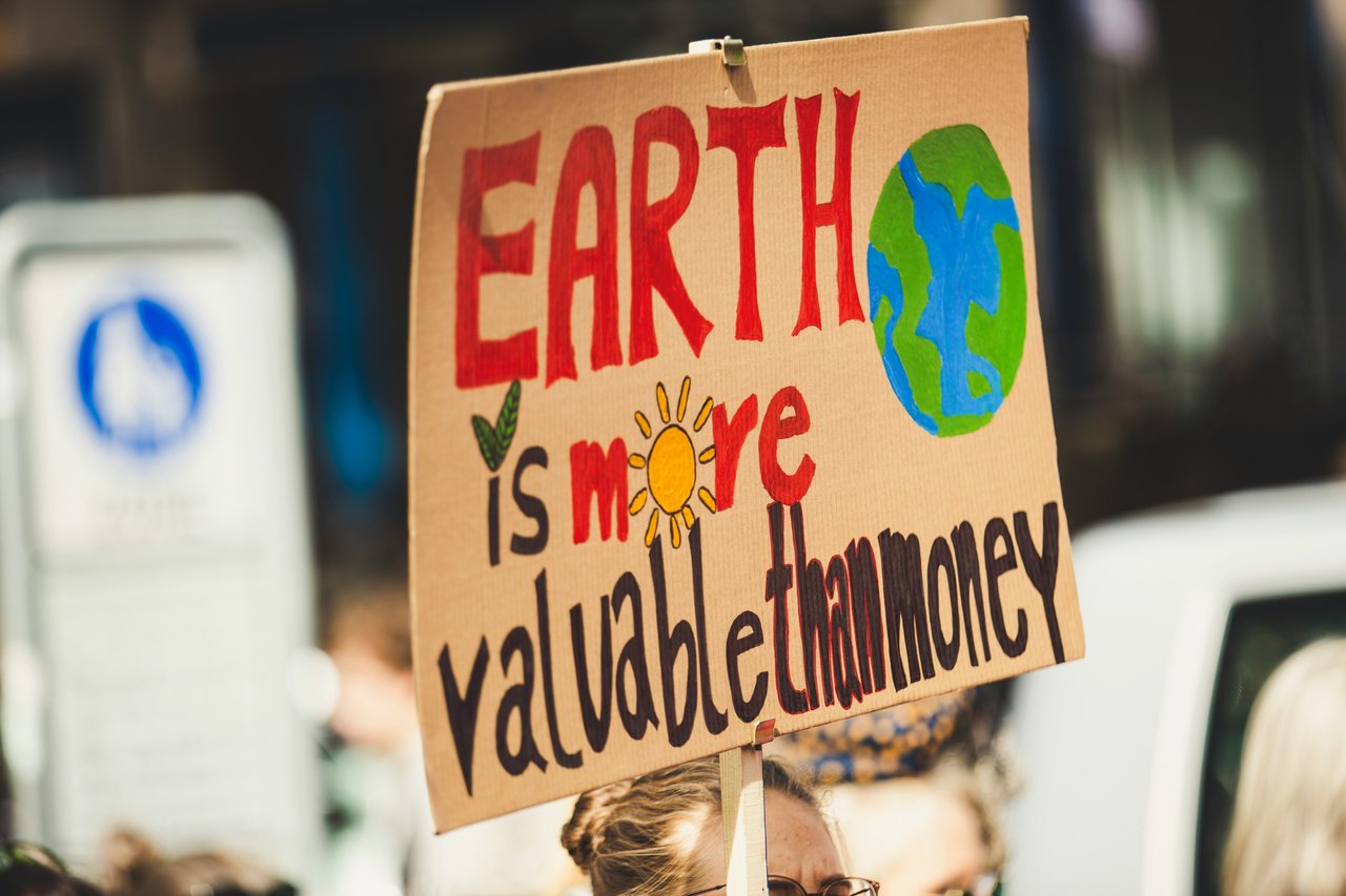 A protest sign that reads "earth is more valuable than money"