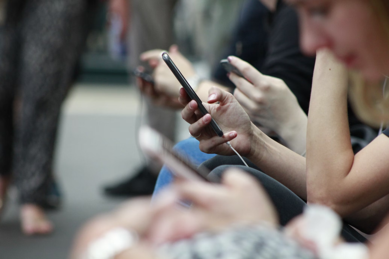 A row of people all staring at their smartphones