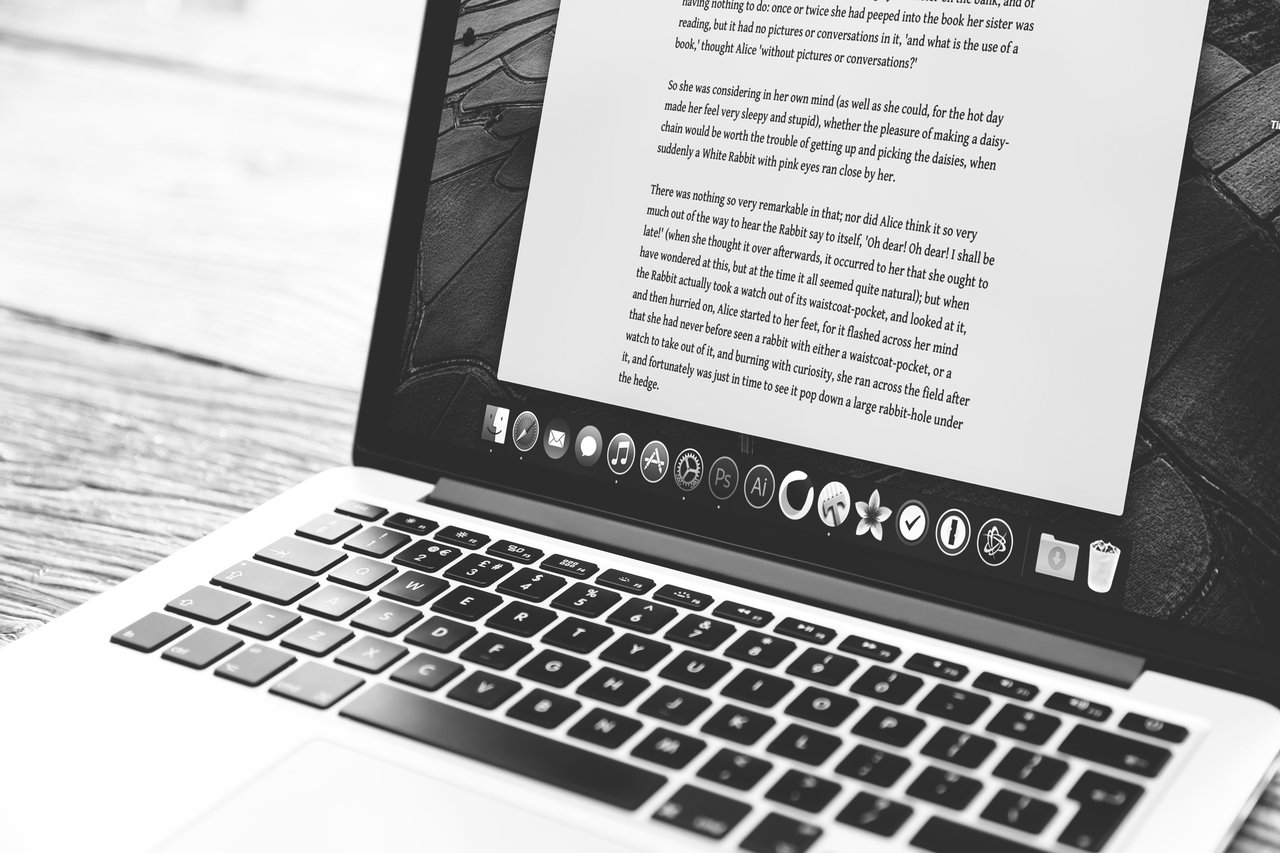 A black and white image of a laptop with a word document open on the screen.