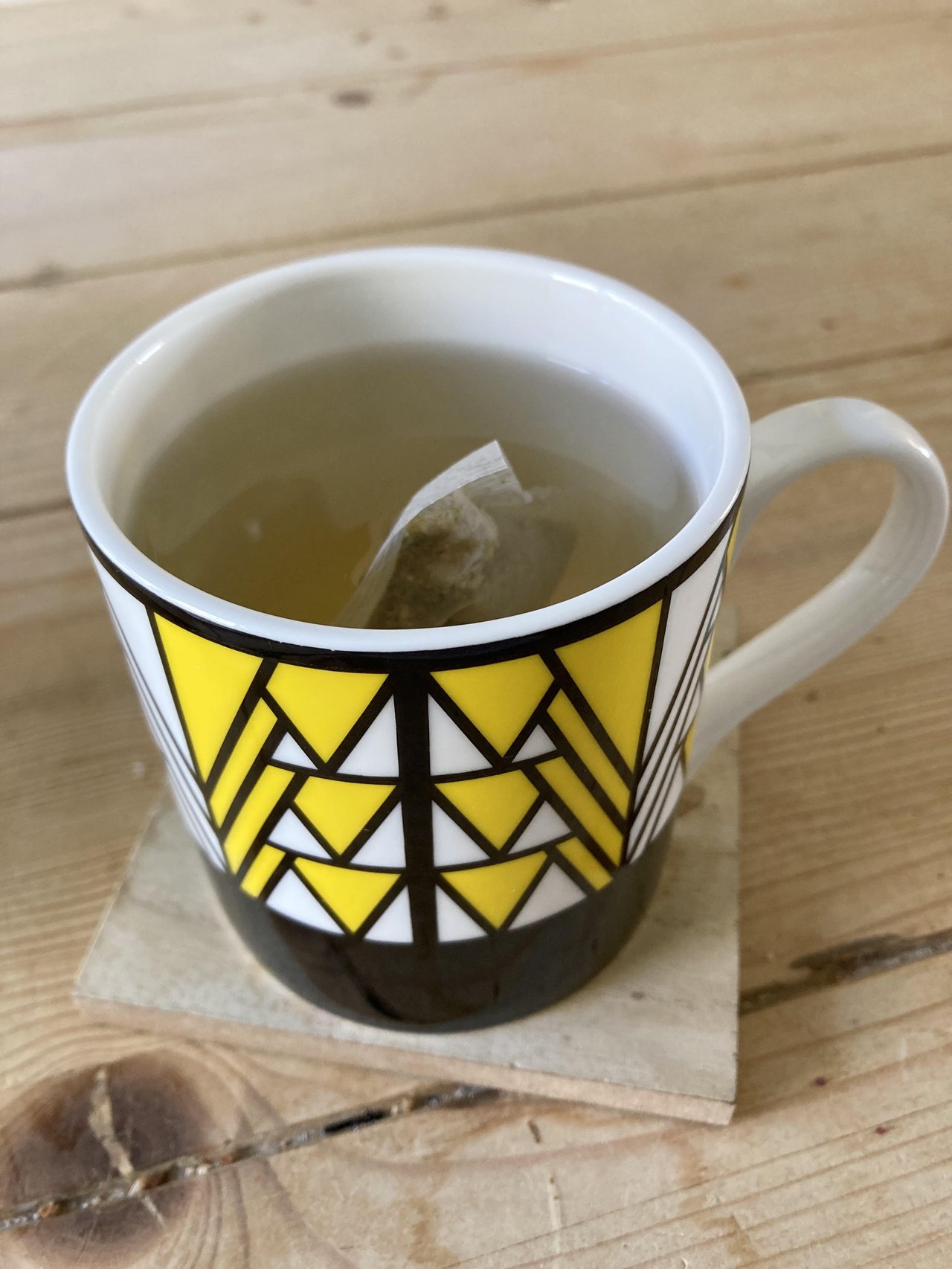 An image of a yellow and black mug containing lemon & ginger tea